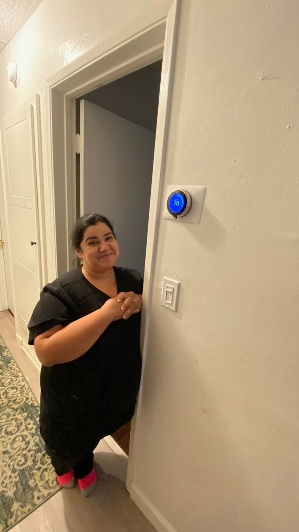 a customer looking happy beside her new thermostat